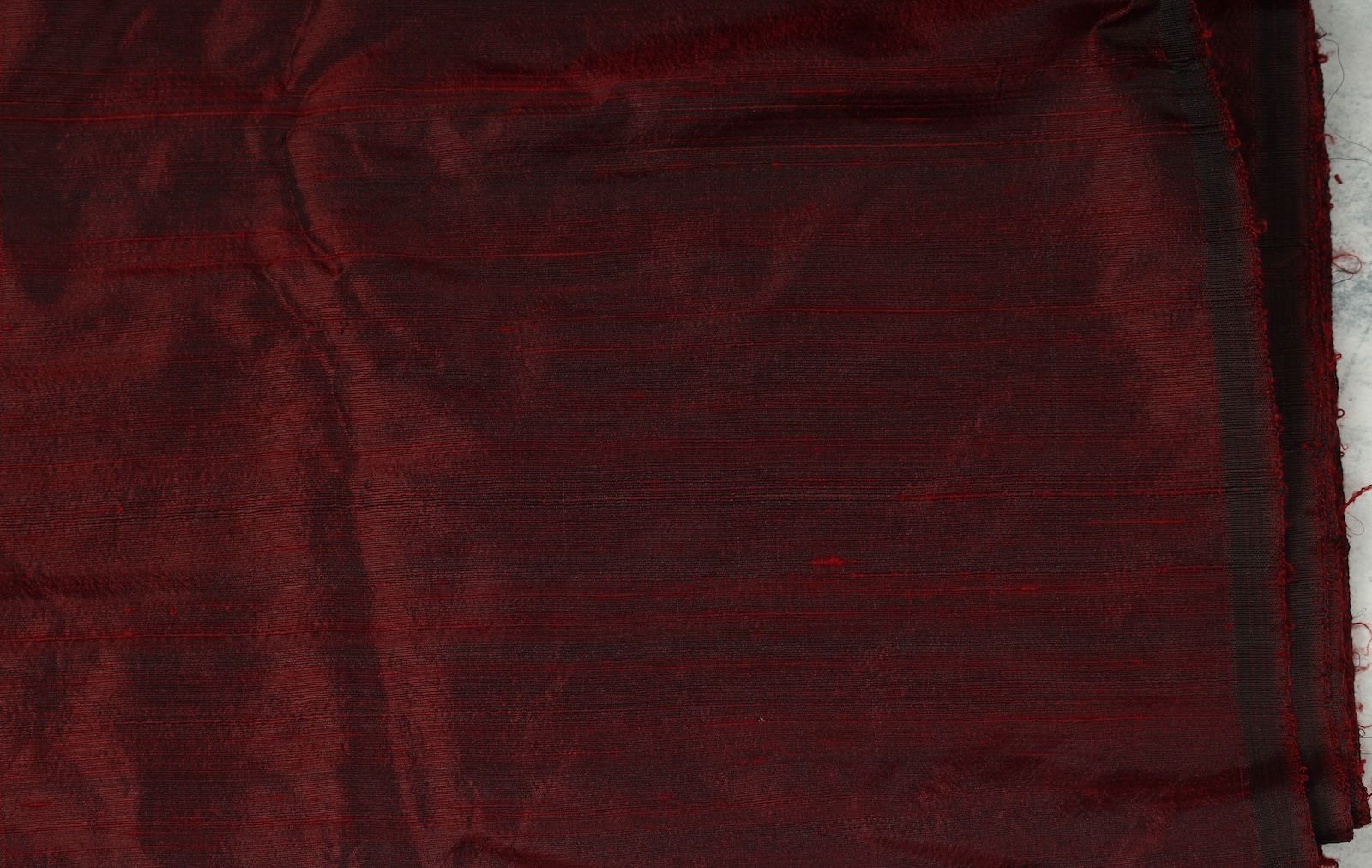 Ruby red Dupion silk fabric laid flat showing colour and natural texture.
