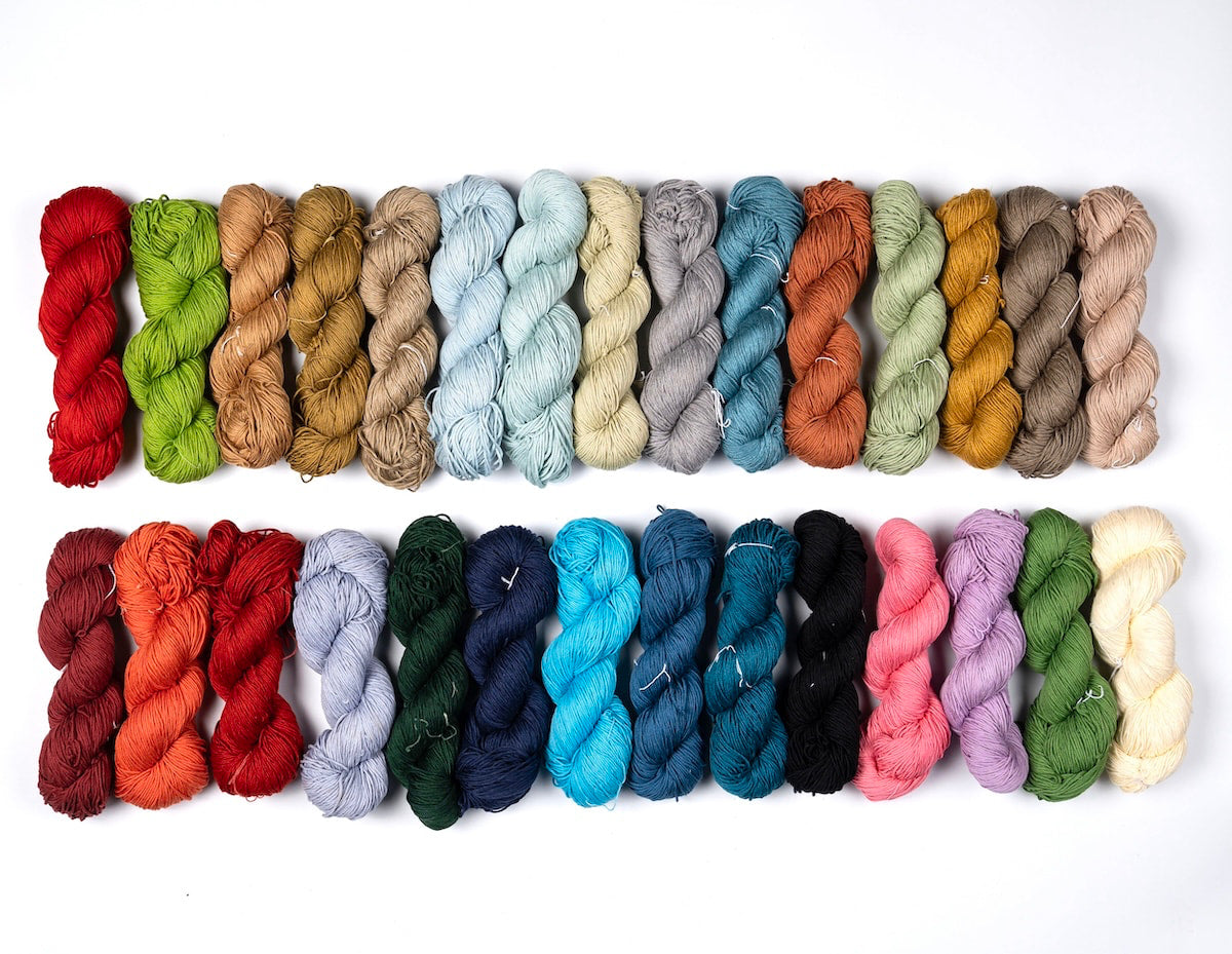 100% Mercerized Cotton Yarn – flatlay showing all 29 colorful shades together on a white background.