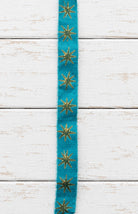 Close-up of teal block printed silk ribbon with repeating gold star pattern
