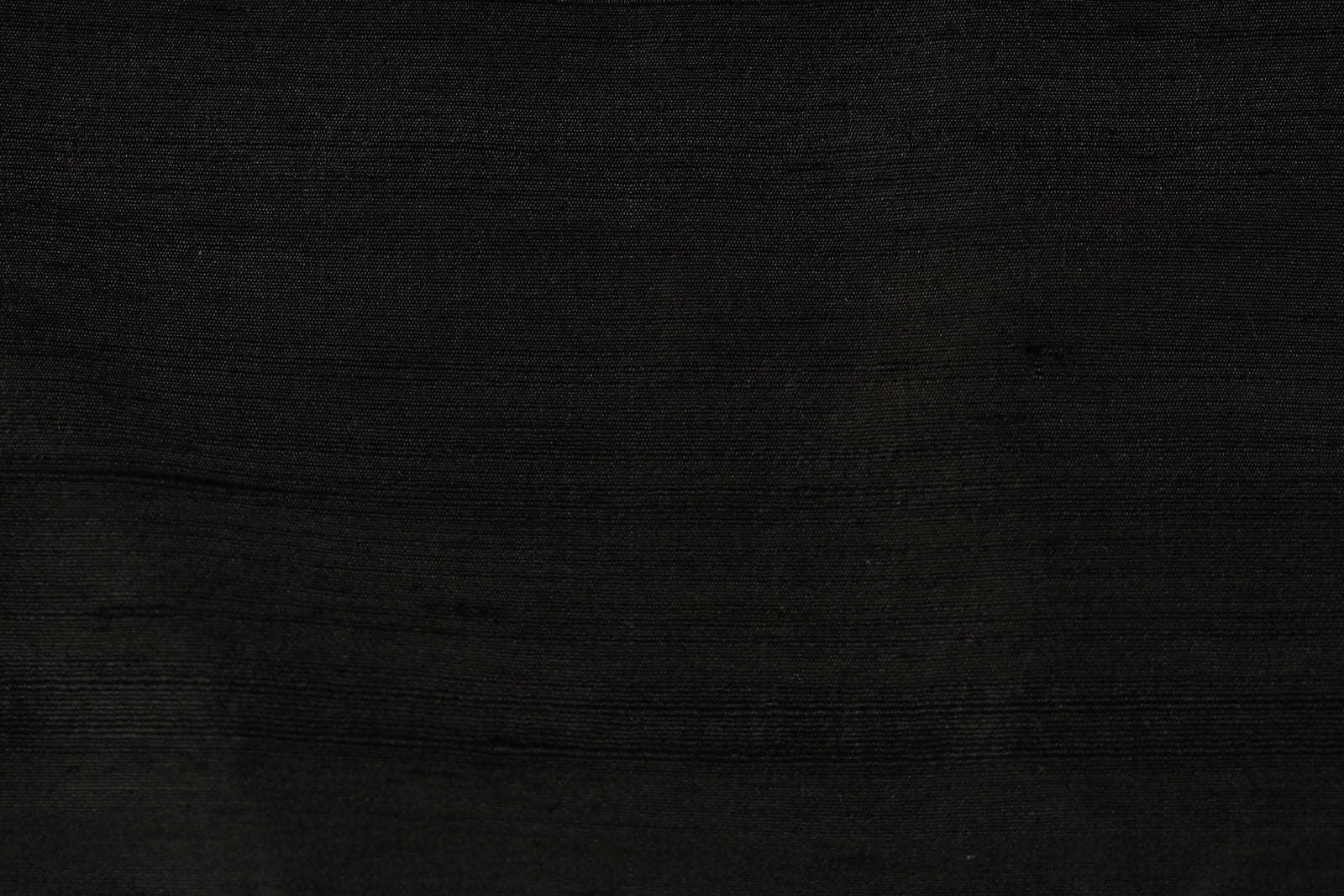 Close-up of Black Dupion Silk Fabric showing natural slub texture, woven silk detail, and rich black colour