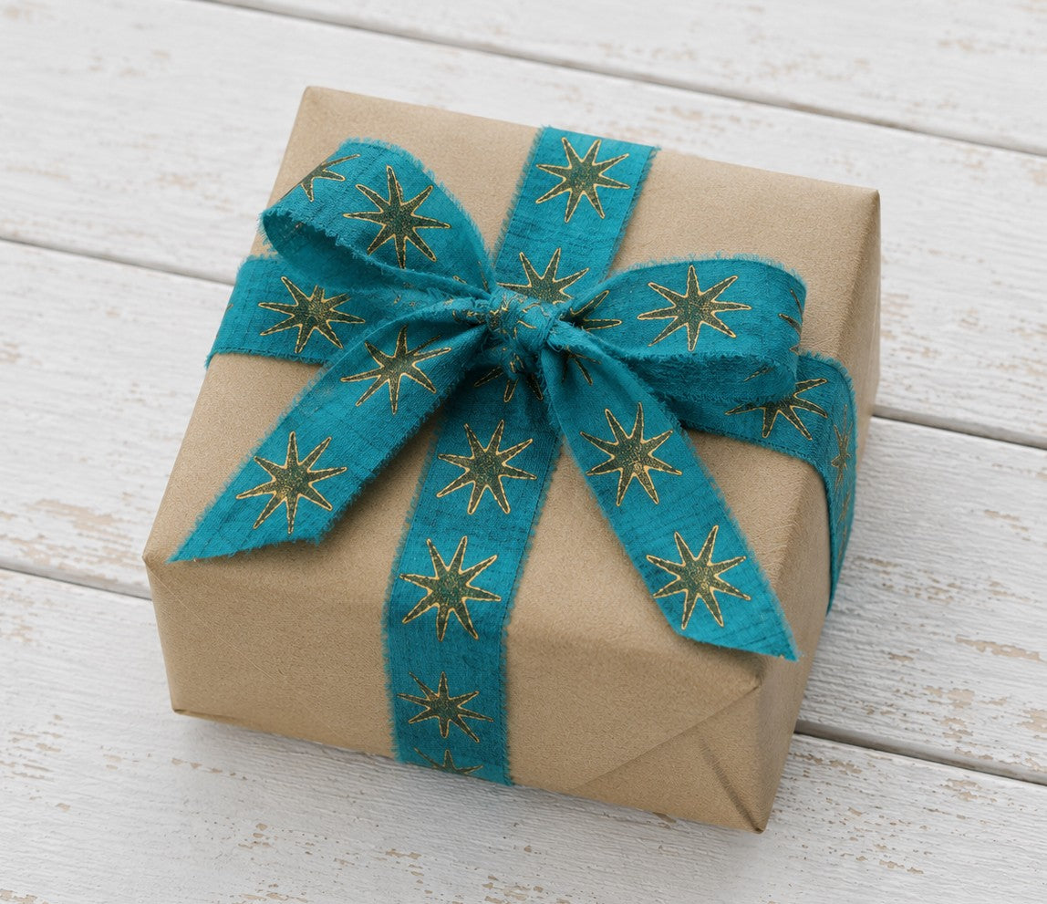 Gift wrapped package decorated with teal block printed silk ribbon and gold star design
