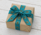 Gift wrapped package decorated with teal block printed silk ribbon and gold star design