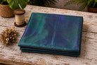 Peacock Lagoon dupion silk fabric folded on a tabletop showing peacock blue and emerald green iridescent raw silk
