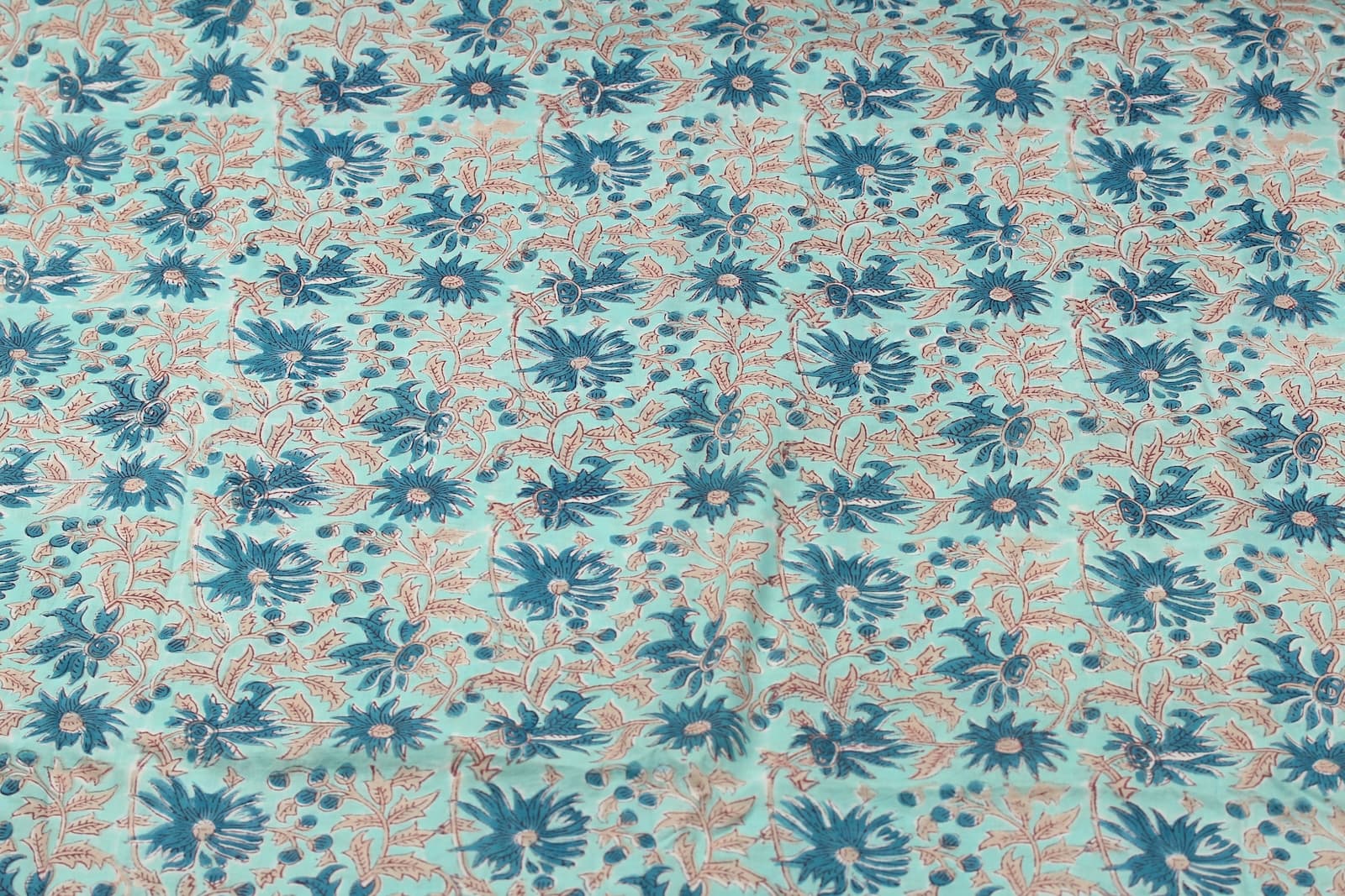 Aqua floral block print cotton fabric with repeating blue flowers, berries and leafy vine motifs