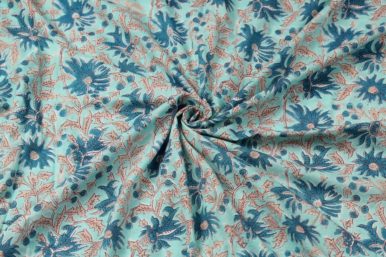 Hand block printed aqua cotton fabric draped to showcase blue floral pattern and soft fabric texture