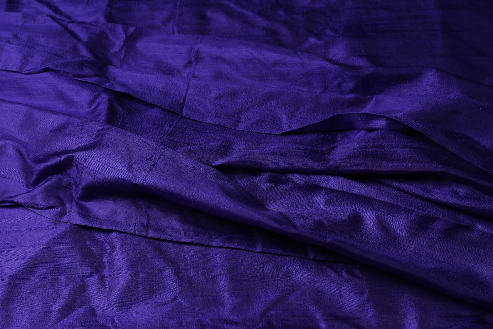 Blue Violet Dupion Silk Fabric displayed with soft folds revealing natural silk texture, luminous finish, and vibrant blue-violet tones