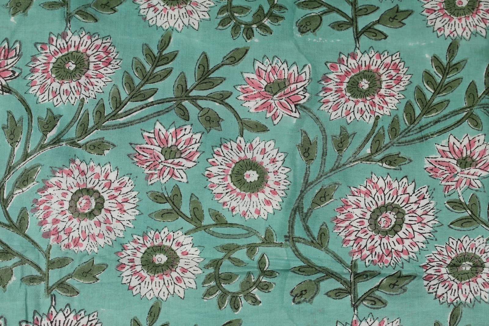 Close-up of blush pink chrysanthemum flowers and trailing olive vines on hand printed cotton fabric