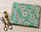Folded hand block printed cotton fabric with blush pink chrysanthemum flowers on a soft aqua background