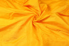 Golden Marigold Dupion Silk Fabric arranged in elegant swirling folds highlighting its lustrous finish and natural dupion silk texture