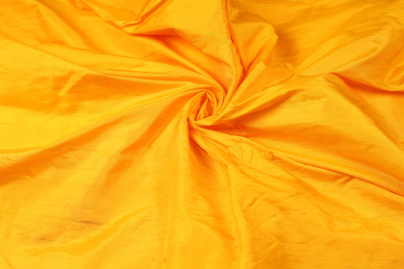 Golden Marigold Dupion Silk Fabric arranged in elegant swirling folds highlighting its lustrous finish and natural dupion silk texture