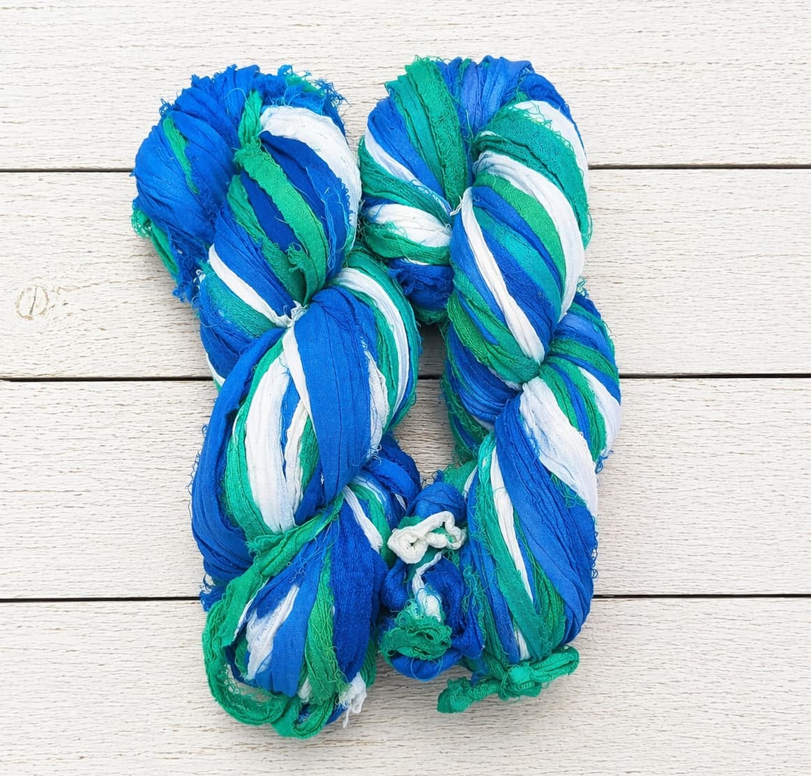 Two skeins of Ocean Breeze recycled silk ribbon yarn for weaving and crochet projects