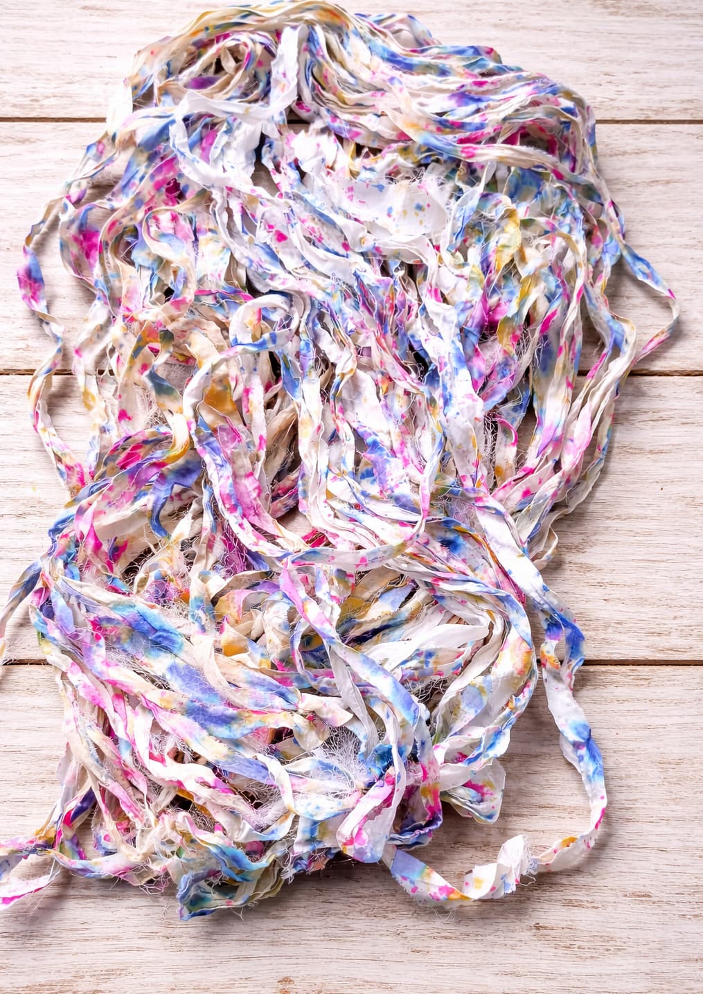 Loose strands of Cotton Candy Confetti sari silk ribbon yarn showing watercolor-inspired colors