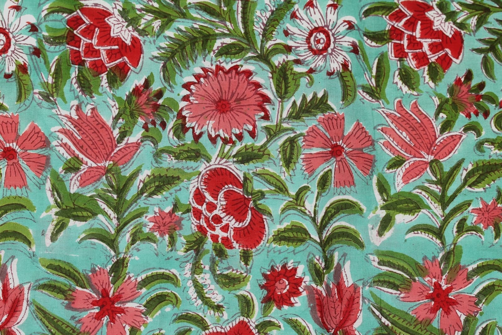 Close-up detail of Coral Wildflower Meadow block printed cotton fabric showing hand block printed floral motifs