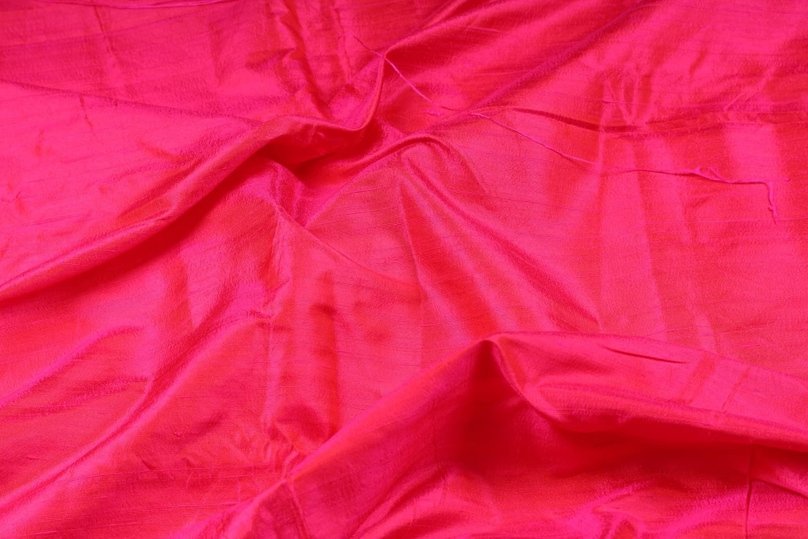 Draped Electric Fuchsia dupion silk fabric displaying natural slub texture and vibrant pink sheen