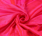 Electric Fuchsia dupion silk fabric arranged in a swirl highlighting bright pink colour and silk texture