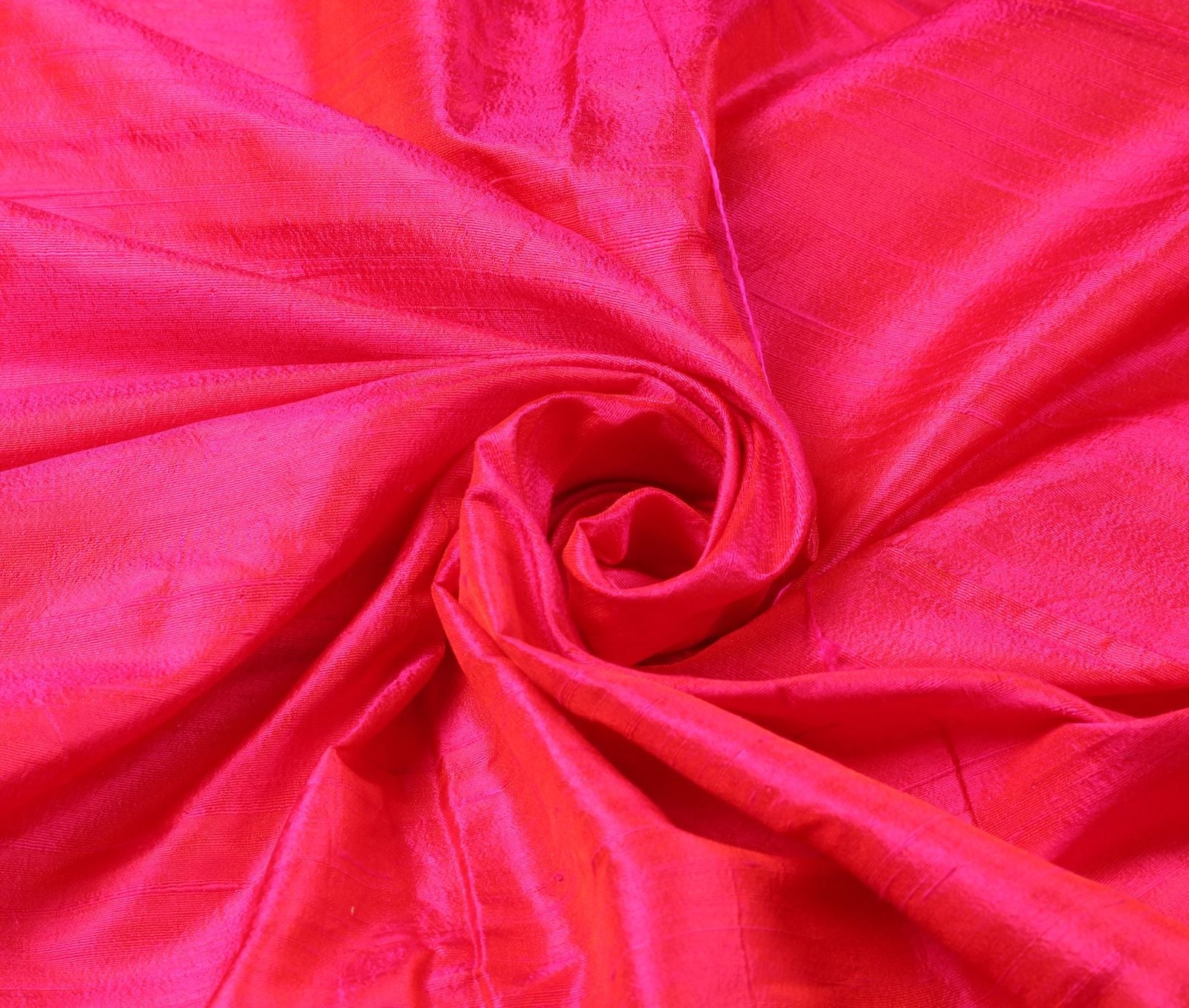 Electric Fuchsia dupion silk fabric arranged in a swirl highlighting bright pink colour and silk texture