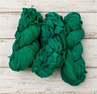 Multiple skeins of emerald chiffon silk ribbon yarn arranged together