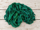 Coiled emerald chiffon silk ribbon yarn showing soft texture and drape