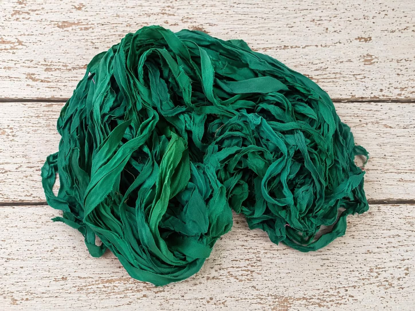 Coiled emerald chiffon silk ribbon yarn showing soft texture and drape
