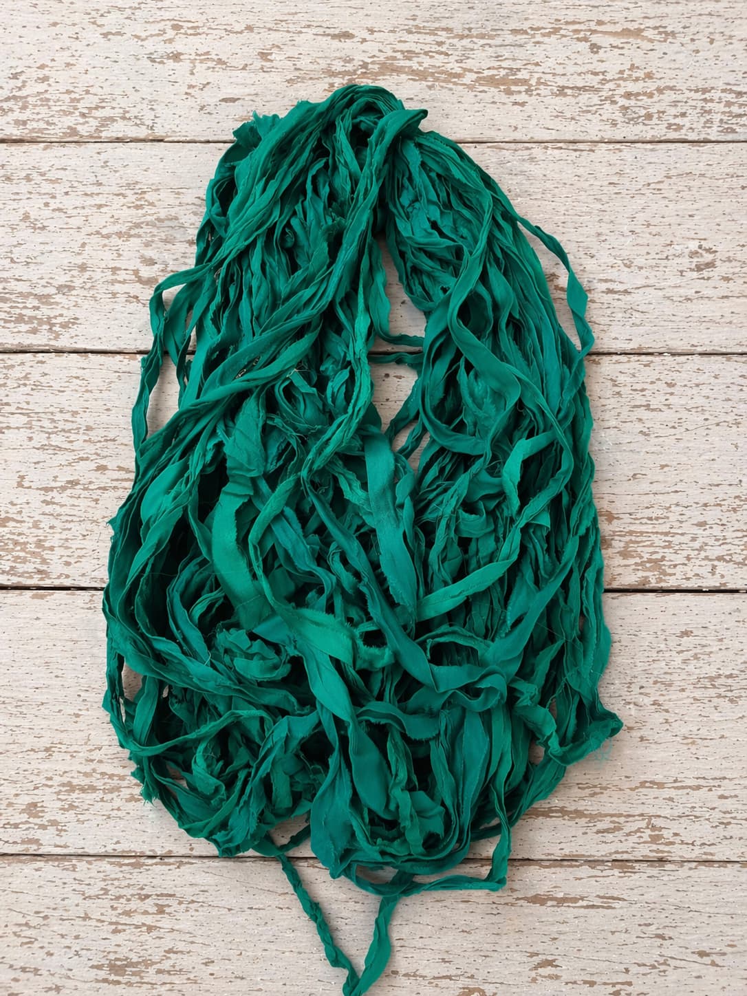 Close-up of emerald chiffon silk ribbon yarn highlighting soft chiffon weave and rich green color