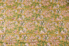 Golden floral block print cotton fabric featuring repeating pink flowers and trailing green botanical vines