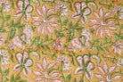 Close-up of pink jasmine-inspired floral motifs and leafy vines on golden hand block printed cotton fabric