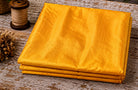 Golden Marigold Dupion Silk Fabric folded to showcase its rich golden yellow colour, natural silk texture, and elegant sheen
