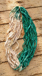 Loose seafoam and ivory sari silk ribbon yarn showing flowing texture and drape
