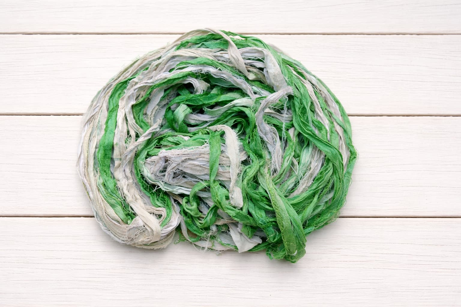 Coiled spring green sari silk ribbon yarn showing soft texture and color variation
