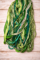Close-up texture of recycled sari silk ribbon yarn in emerald, sage and teal green shades