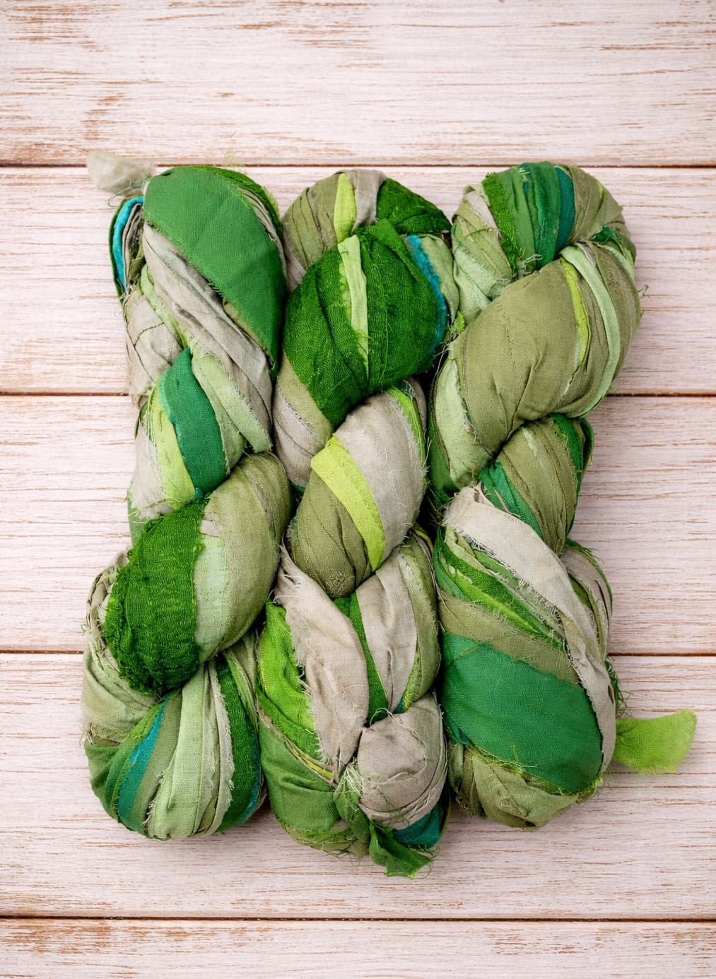 Multiple skeins of Emerald Meadow sari silk ribbon yarn arranged together