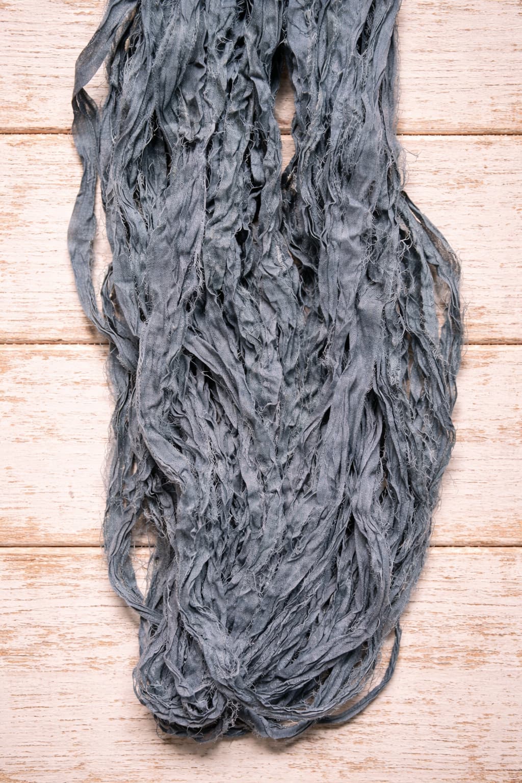 Long strands of storm grey sari silk ribbon showing soft texture and naturally frayed edges.