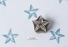 Tiny minimalist hand-carved starfish wooden stamp on off white background
