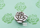 Hand carved rose wooden printing stamp creating repeating rose pattern on fabric.