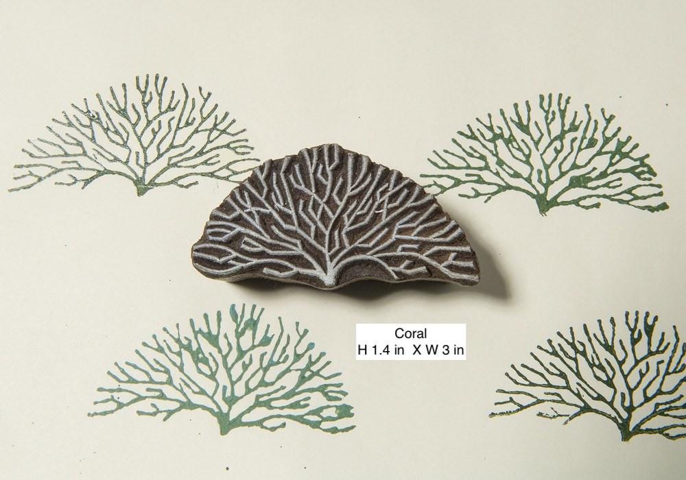 Hand carved coral-inspired wooden printing block creating organic sea life patterns on paper.