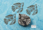 Decorative peaceful bird wood block stamp with floral details printed on blue handmade paper.