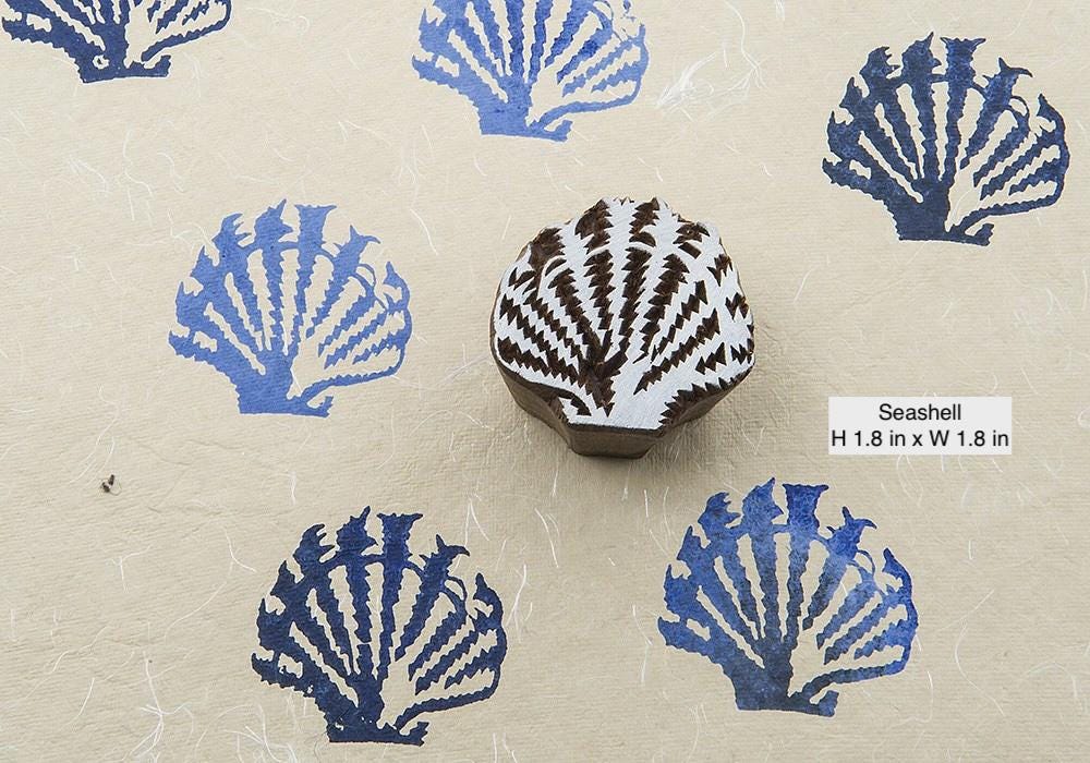 Hand carved seashell wooden block printing stamp shown with repeated fabric print impressions