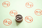 Hand carved yin yang wooden printing block with balance symbol stamped on soft green background