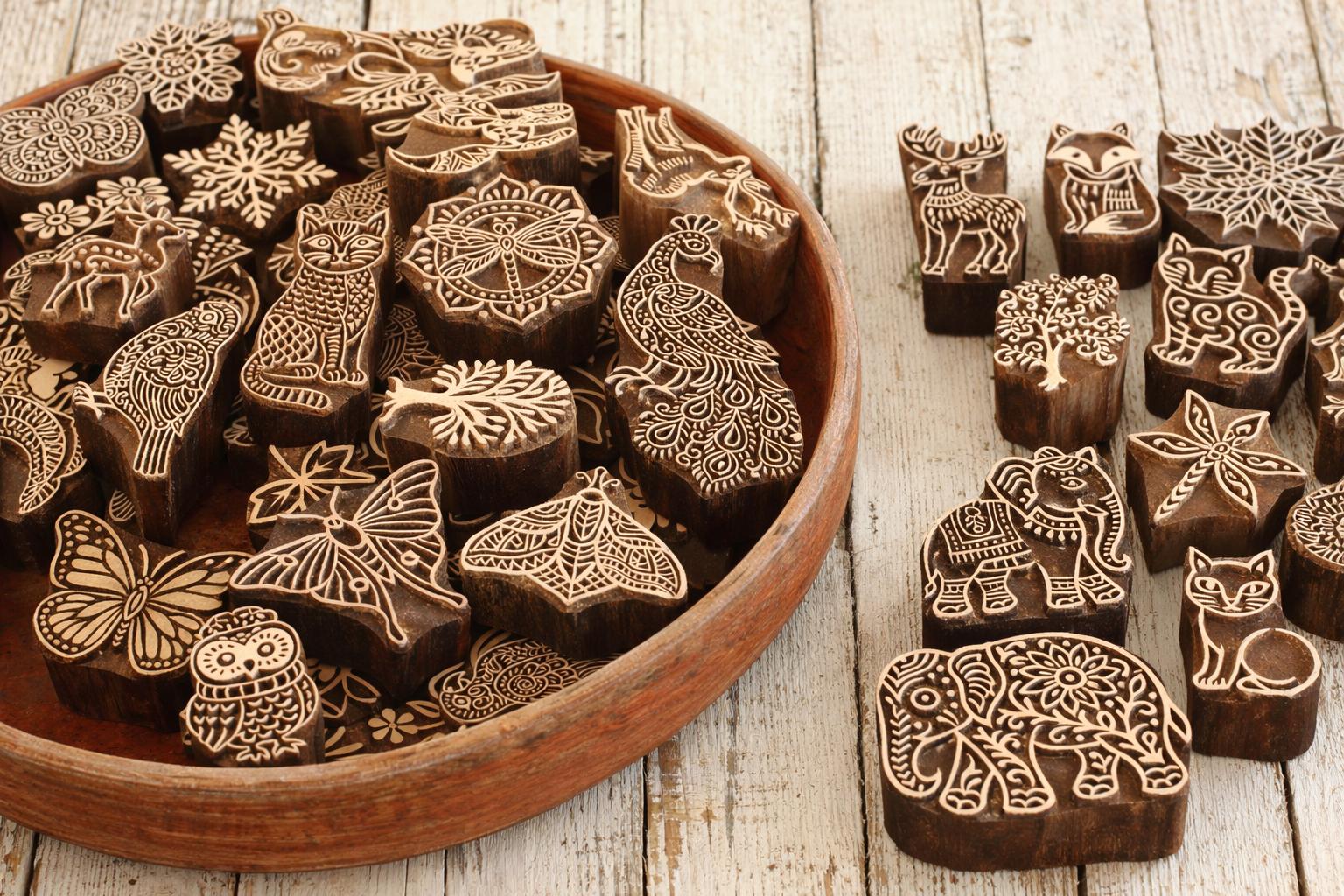 Assorted hand carved wooden printing blocks including animals, florals and nature designs arranged in a wooden tray for custom bundle offer.