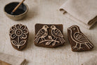 Hand carved wooden printing blocks featuring flower, single bird, and love birds design on rustic background