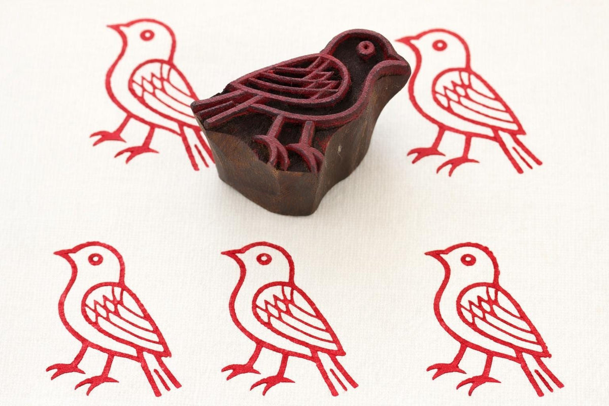 Hand carved wooden bird printing block with red stamped pattern on fabric