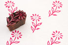 Hand carved Indian floral wood block stamp with pink fabric print pattern on white textile