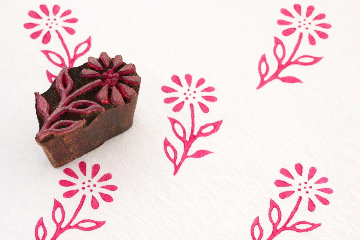 Hand carved Indian floral wood block stamp with pink fabric print pattern on white textile