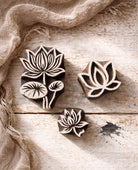 Set of three hand carved wooden lotus block printing stamps displayed on rustic white wooden surface with natural linen fabric.