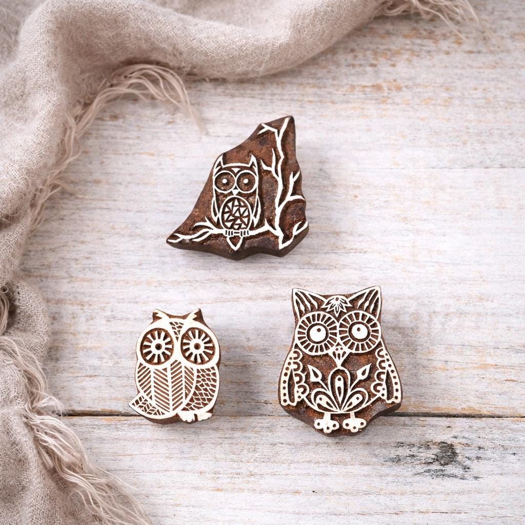 Set of three hand carved wooden owl printing blocks with traditional Indian folk designs on a white background