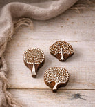 Three wooden tree-shaped stamps with detailed designs. The stamps are brown with white detailing, showcasing various tree styles. One stamp has a long handle, while the others are more compact. Suitable for block printing on paper, clay and textile
