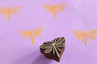 Hand carved dragonfly wooden printing block with repeated dragonfly prints on soft purple paper