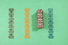 Hand carved wooden heritage motif border block printing stamp creating repeating vertical pattern on green background.