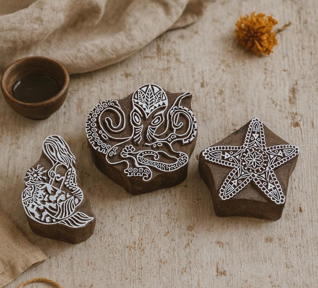 Set of three hand carved wooden block printing stamps featuring octopus, starfish, and mermaid designs on neutral background.