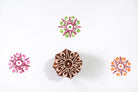 Hand carved wooden eight point star block printing stamp with colorful star impressions on white background.